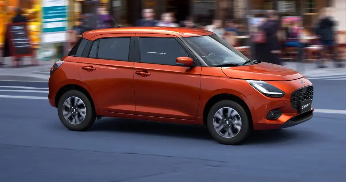 Suzuki Swift Híbrido color naranja brillante conduciendo por una calle urbana